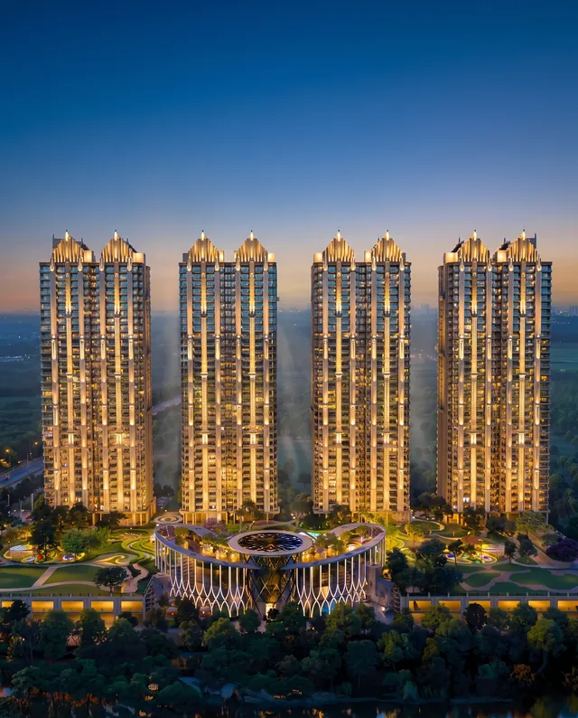 Gaur Alaris — the eight art-deco-crowned towers lit at blue hour, Club Regalia at the centre (builder render, artistic visualization)